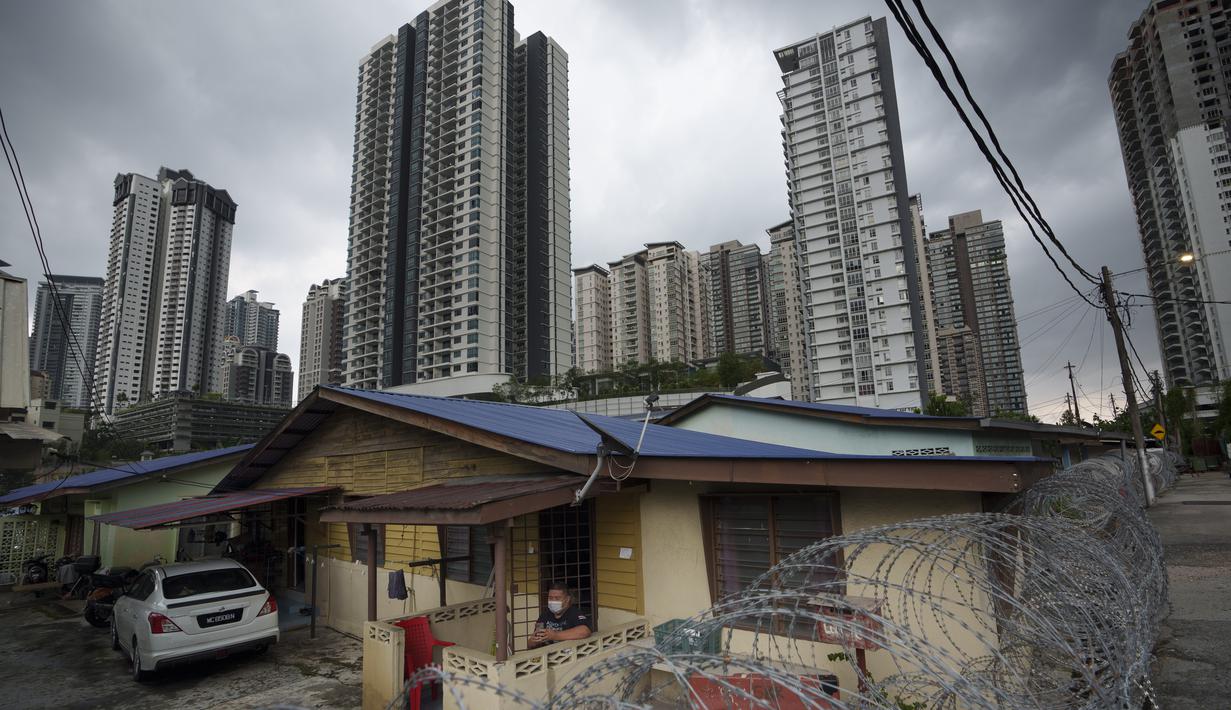 Warga duduk di luar rumahnya di daerah Segambut Dalam ditempatkan di bawah EMCO di Kuala Lumpur, Malaysia (27/6/2021). Pemimpin Malaysia mengatakan penguncian total satu bulan yang akan berakhir Senin akan diperpanjang karena infeksi virus corona tetap tinggi. (AP Photo/Vincent Thian)