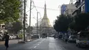 Orang-orang berjalan di sebelah Pagoda Shwedagon di jalan kosong di Yangon, Myanmar pada Senin (1/2/2021). Militer Myanmar mengumumkan satu tahun pemberlakuan situasi darurat setelah militer mengkudeta kekuasaan sipil. (STR/AFP)