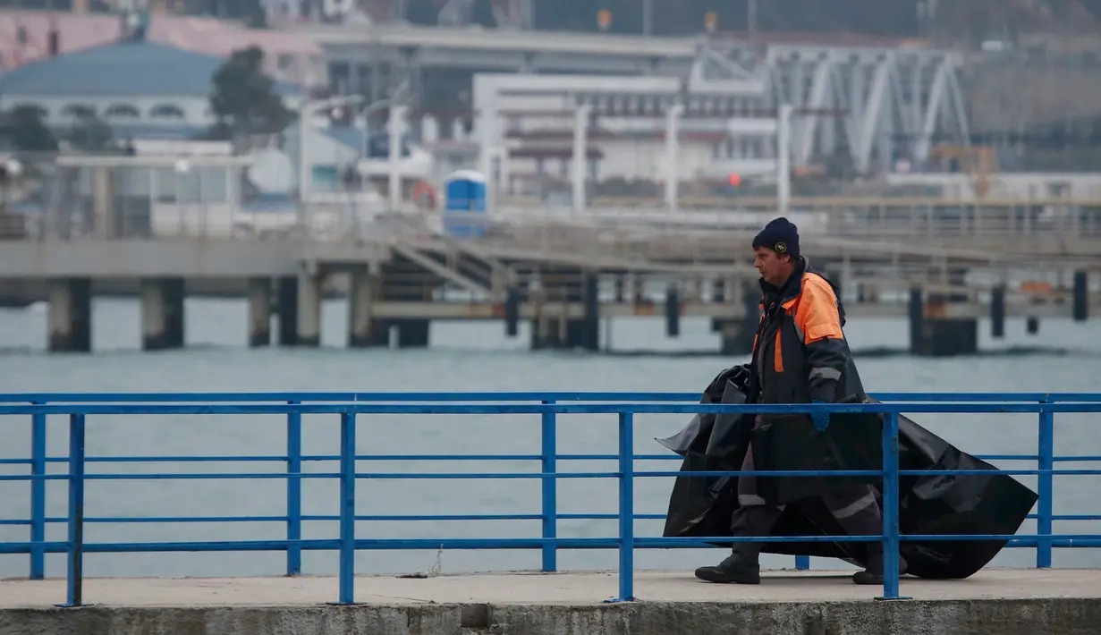 Seorang anggota Kementerian Pertahanan Rusia membawa kantong plastik menuju  dermaga tidak jauh dari kecelakaan pesawat militer Rusia Tu-154 di Laut Hitam di pinggiran Sochi, Rusia (25/12). (REUTERS/Maxim Shemetov)