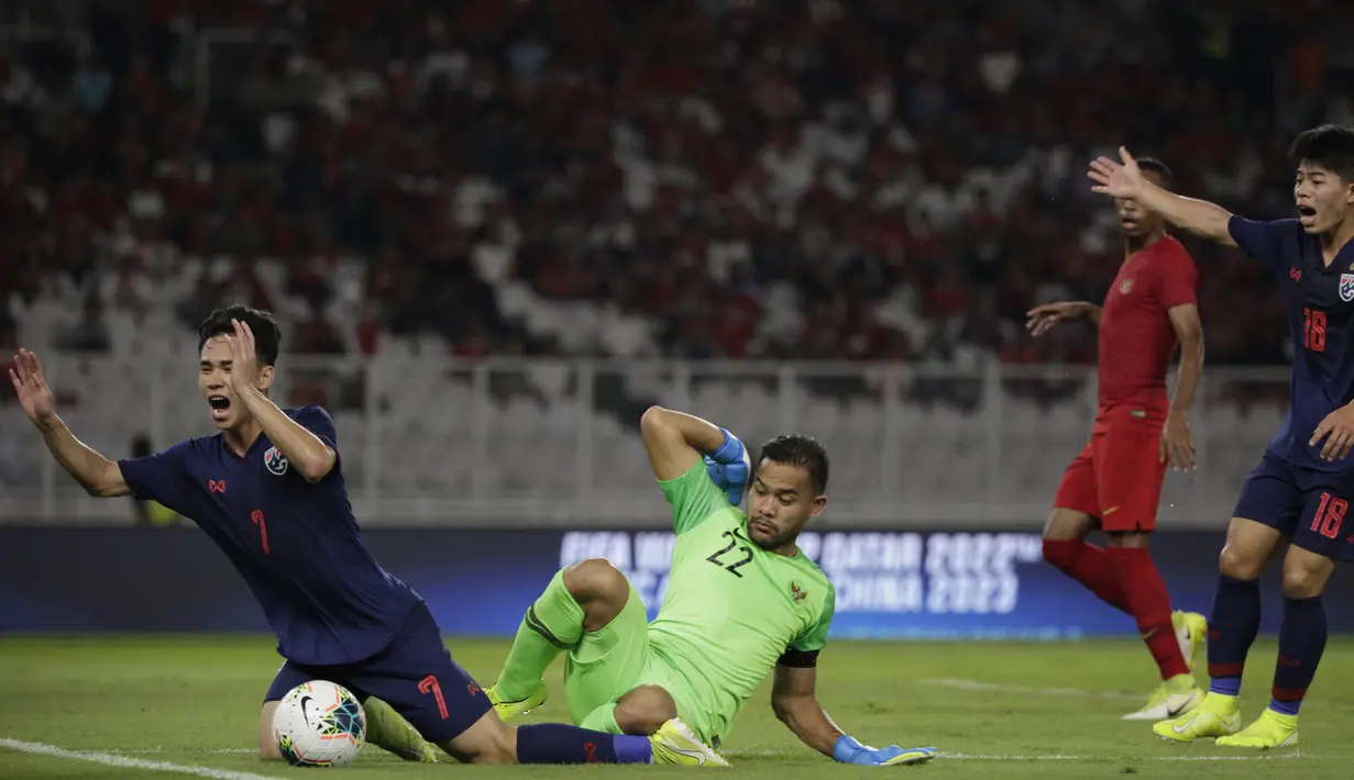 Kiper Timnas Indonesia, Andritany Ardhiyasa, menjatuhkan gelandang Thailand, Supachok Sarachat pada laga Kualifikasi Piala Dunia 2022 di SUGBK, Jakarta, Selasa (10/9). Indonesia kalah 0-3 dari Thailand. (AFP/Vitalis Yogi Trisna)