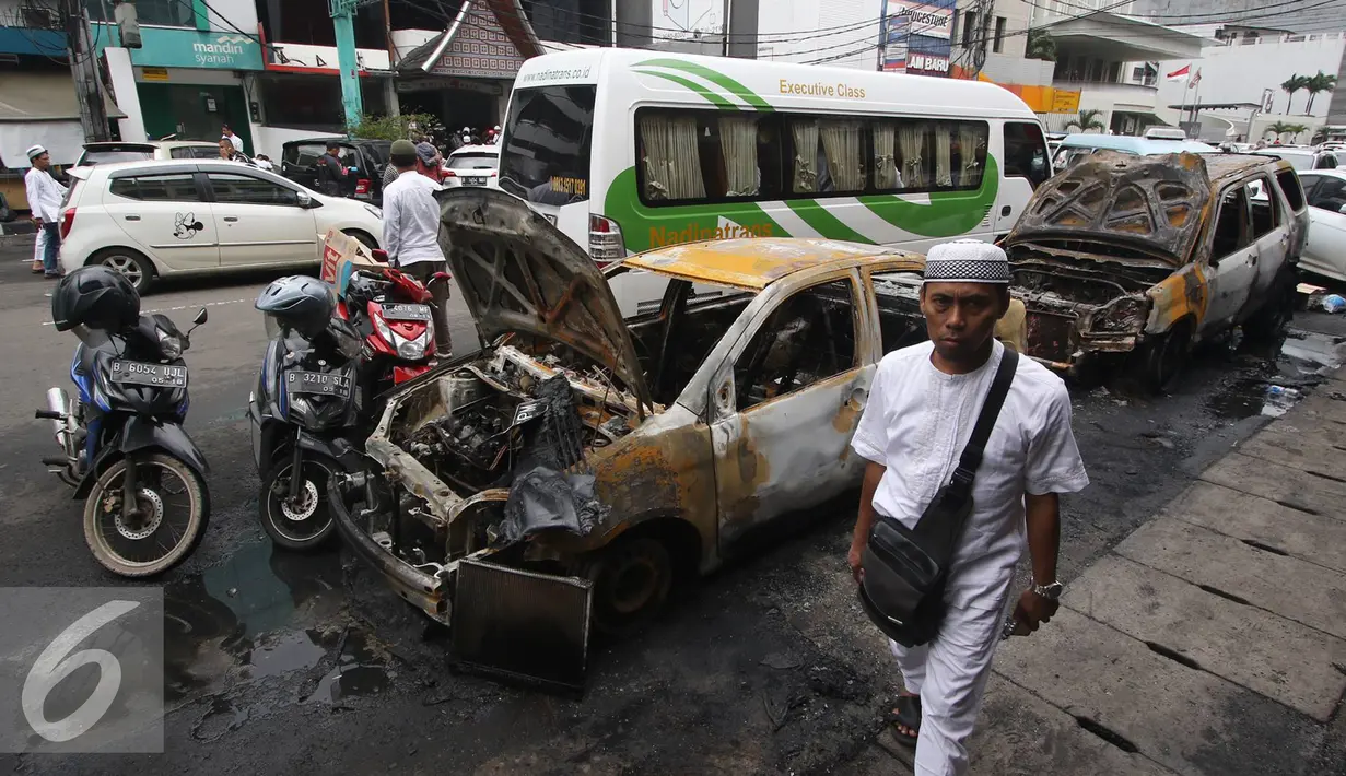 Seorang pria melintas di dekat mobil yang hangus terbakar di Pecenongan, Jakarta, Sabtu (11/2). Dalam kejadian tersebut tidak ada korban jiwa dan kerugian materiil belum bisa diperkirakan. (Liputan6.com/Immanuel Antonius)