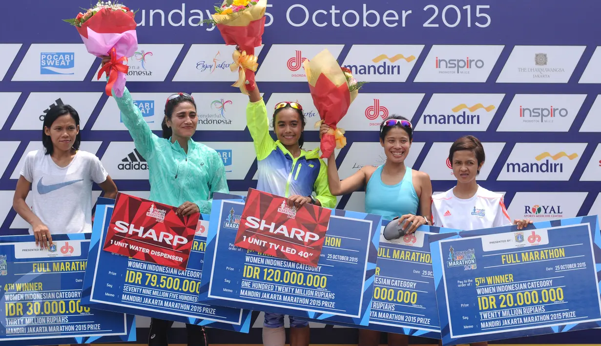 Pelari Nasional, Triyaningsih (tengah) mengangkat tangan usai menerima hadiah lomba lari Jakarta Marathon 2015 di Silang Monas Jakarta, Minggu (25/10/2015). Triyaningsih mencatat waktu tiga jam lima menit 24 detik. (Liputan6.com/Helmi Fithriansyah)