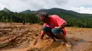 Seorang pria mencoba untuk menemukan sandalnya yang tertimbun lumpur setelah longsor di Desa Elangipitiya, Aranayaka, Sri Lanka (19/5). Ratusan warga dikabarkan hilang akibat tanah longsor tersebut. (REUTERS/Dinuka Liyanawatte)