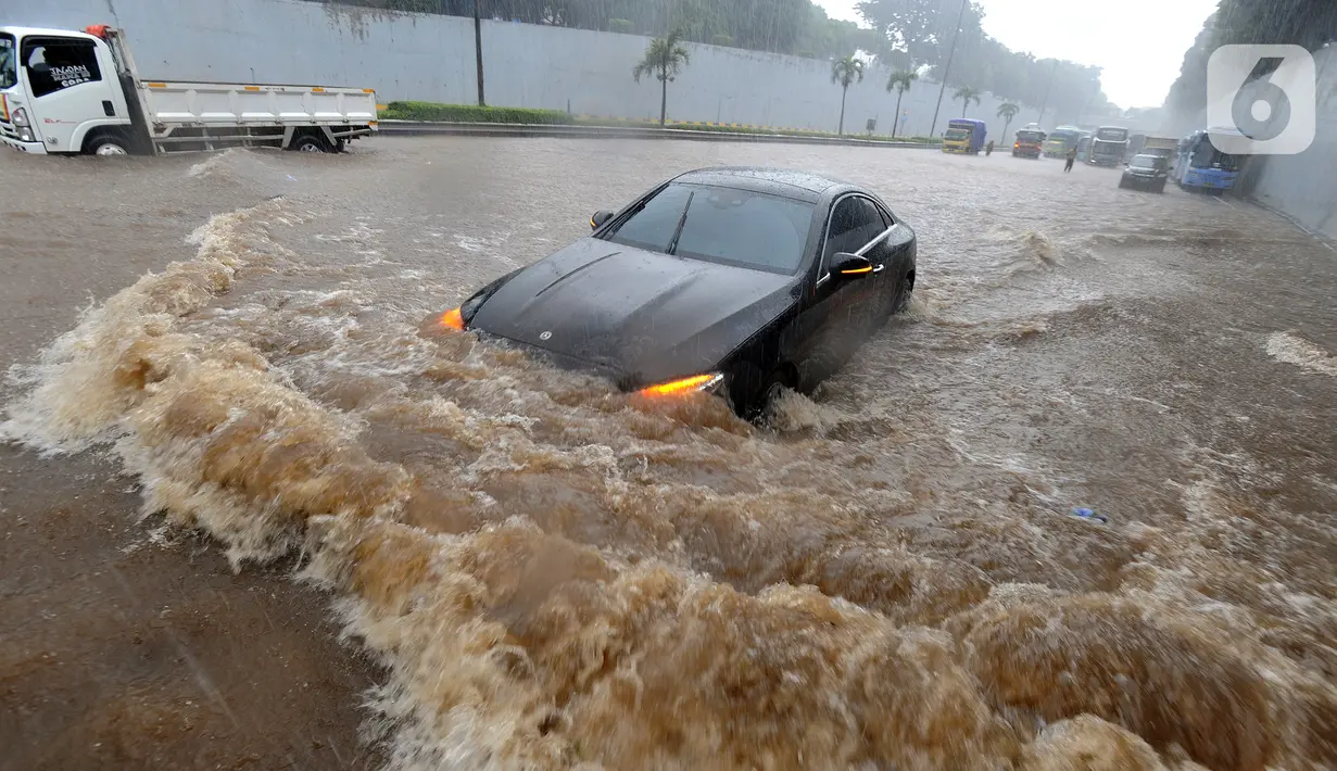 Mobil menerjang banjir yang menggenangi Jalan Tol JORR di kawasan TB Simatupang, Jakarta Selatan, Sabtu (20/2/2021). Banjir terjadi akibat luapan Kali Serua yang berada di pinggir jalan tol. (merdeka.com/Arie Basuki)