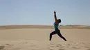 Seorang wanita mengikuti kelas yoga yang digelar di gurun Samalayuca, negara bagian Chihuahua, Meksiko, 28 April 2018. Ratusan penggemar yoga mengikuti latihan bersama di bawah terik matahari dan beralaskan pasir. (AFP PHOTO / HERIKA MARTINEZ)