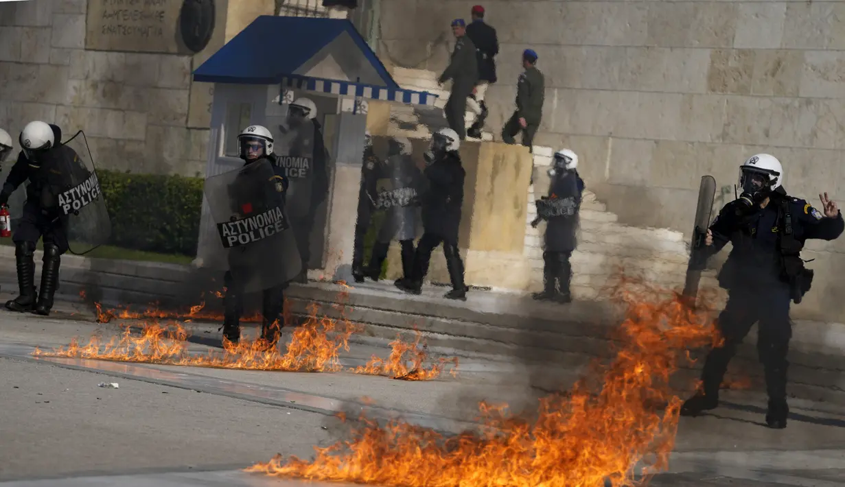 Bom molotov yang dilemparkan oleh pengunjuk rasa meledak di dekat polisi anti huru hara di luar Parlemen Yunani selama bentrokan di Athena, Yunani, Rabu (9/11/2022). Ribuan pengunjuk rasa berbaris melalui jalan-jalan Athena dan kota Thessaloniki di Yunani utara sebagai pekerja publik dan beberapa sektor swasta meninggalkan pekerjaan untuk pemogokan umum 24 jam terhadap kenaikan harga.  (AP Photo/Petros Giannakouris)