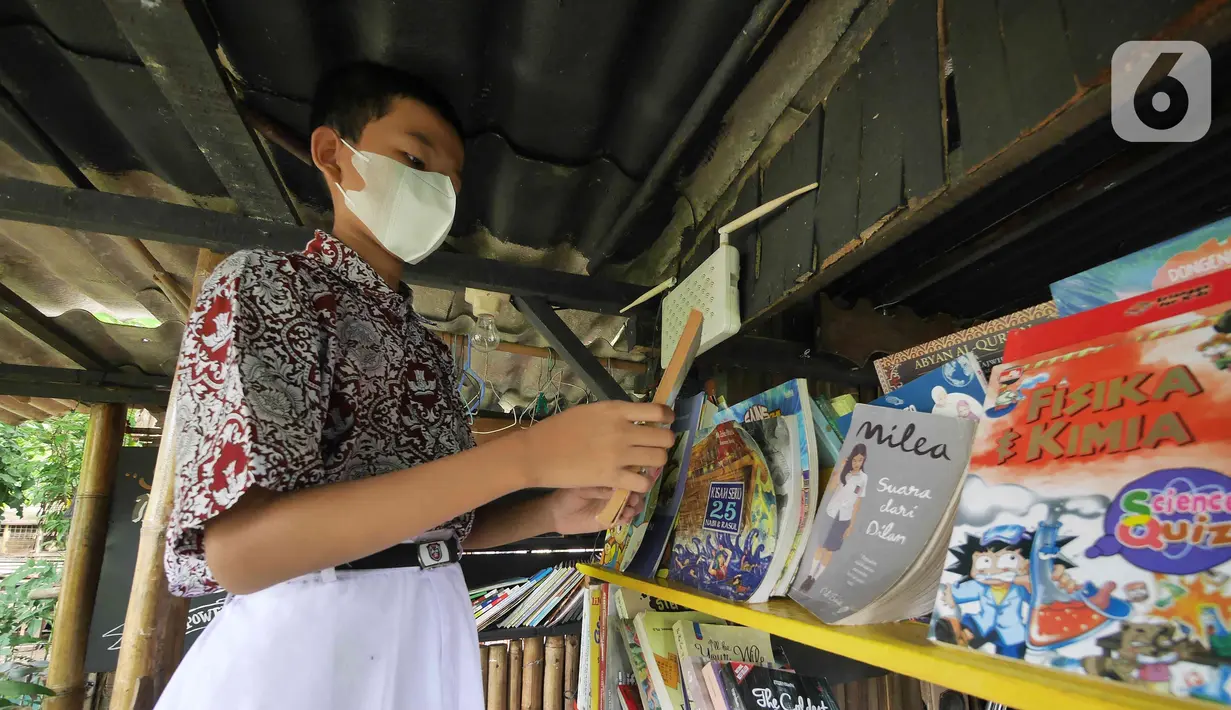 Seorang anak memilih buku untuk dibaca di pustaka mini Bale Buku, Kramat Jati, Jakarta Timur, Kamis (20/01/2022). Bale buku yang diresmikan pada Sabtu (15/1) dibangun dari barang-barang bekas tersebut untuk memberi ruang bagi anak-anak serta warga agar gemar membaca. (Liputan6.com/Herman Zakharia)