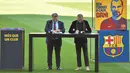 Bek baru Barcelona Dani Alves (kanan) dan presiden Barcelona Joan Laporta menandatangani kontrak pemain, selama upacara presentasi di stadion Camp Nou di Barcelona (17/11/2021). (AFP/Pau Barrena)