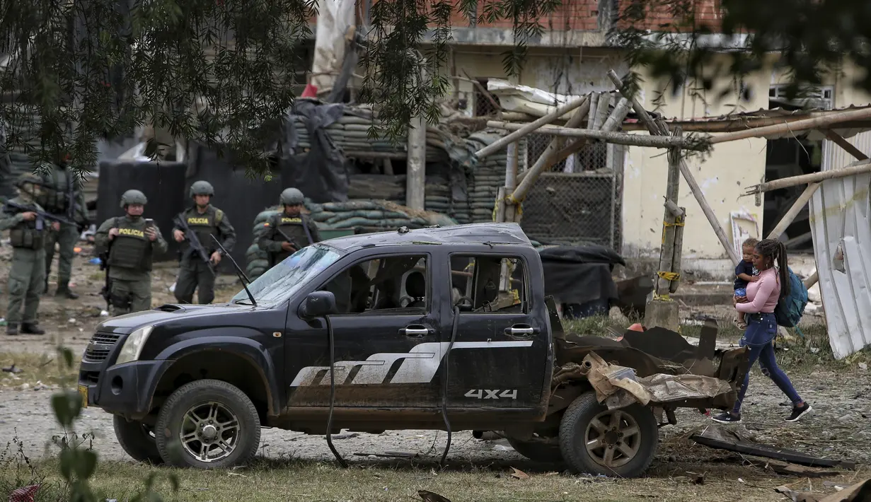 Seorang wanita berjalan di samping reruntuhan bom mobil yang meledak di depan kantor polisi di Timba, Cauca, Kolombia, Minggu, 13 Agustus 2023.  (AP Photo/Andres Quintero)