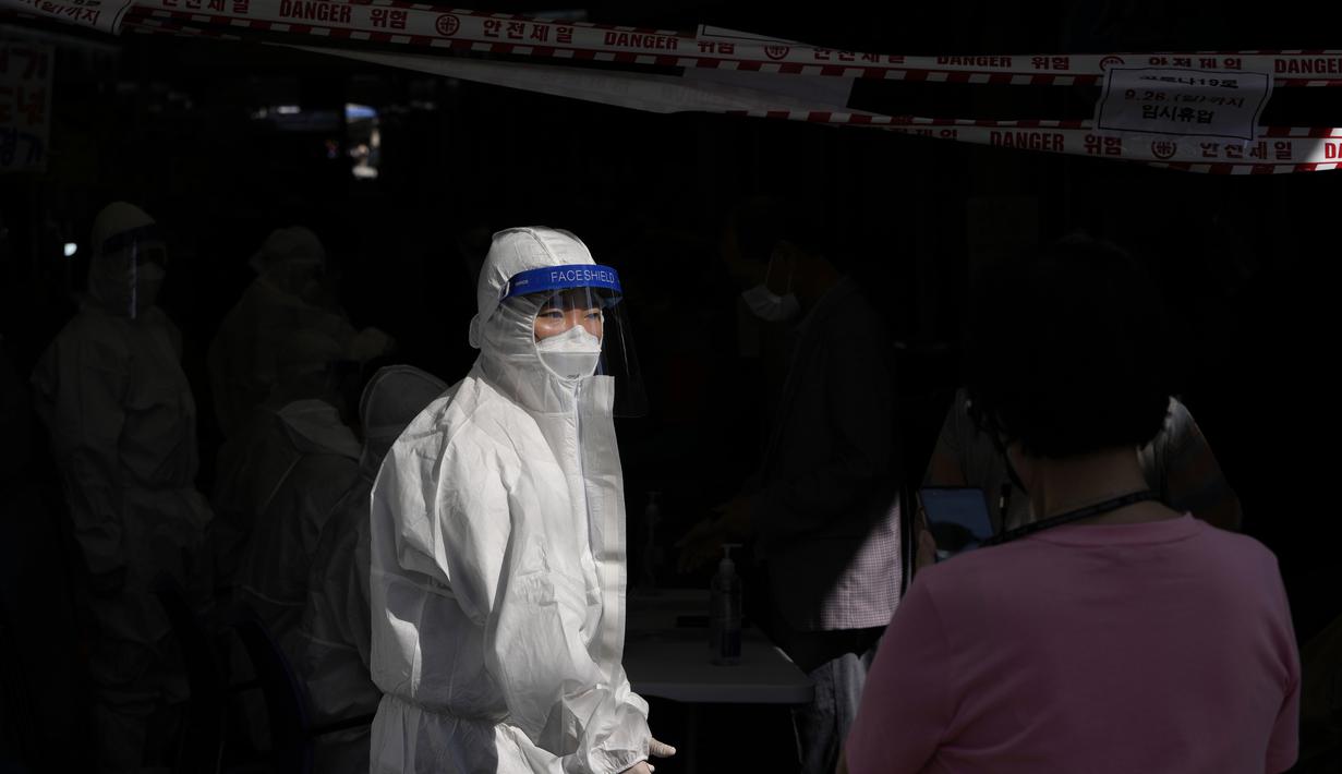 Petugas kesehatan mengenakan alat pelindung membantu pengunjung yang mengantre untuk mendapatkan tes virus corona di klinik skrining sementara virus corona di Seoul, Korea Selatan, Jumat (24/9/2021). (AP Photo/Lee Jin-man)