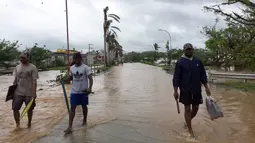 Warga berjalan melewati banjir di kota Ba, wilayah barat Fiji, Rabu (6/4). Zena, dengan kecepatan putaran angin hingga 120 kilometer per jam bergerak ke arah timur menuju Fiji. (NAZIAH ALI/MAI LIFE MAGAZINE /AFP)
