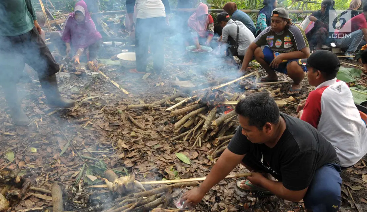 Warga membakar ayam untuk disantap bersama dalam tradisi Sadranan di Sendang Gede Pucung, Pudakpayung, Semarang, Jumat (12/4). Tradisi turun temurun membersihkan mata air dilanjutkan berdoa dan makan bersama itu sebagai rasa syukur warga setempat atas limpahan rezeki. (Liputan6.com/Gholib)
