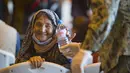 Seorang wanita Afghanistan tersenyum setelah diberi sebotol air usai turun dari pesawat angkatan udara AS di Naval Station di Rota, Spanyol, Selasa (31/8/2021).  Amerika Serikat menyelesaikan penarikannya dari Afghanistan Senin malam, mengakhiri perang terpanjang Amerika. (AP Photo/Marcos Moreno)