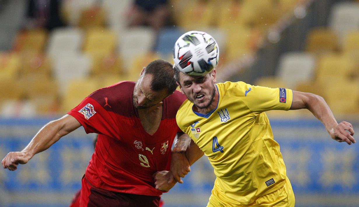 Bek Ukraina, Serhii Kryvtsov, berebut bola dengan penyerang Swiss, Haris Seferovic, pada laga Nations League di Stadion Arena Lviv, Jumat (4/9/2020) dini hari WIB. Ukraina menang 2-1 atas Swiss. (AFP/Anatolii Stepanov)