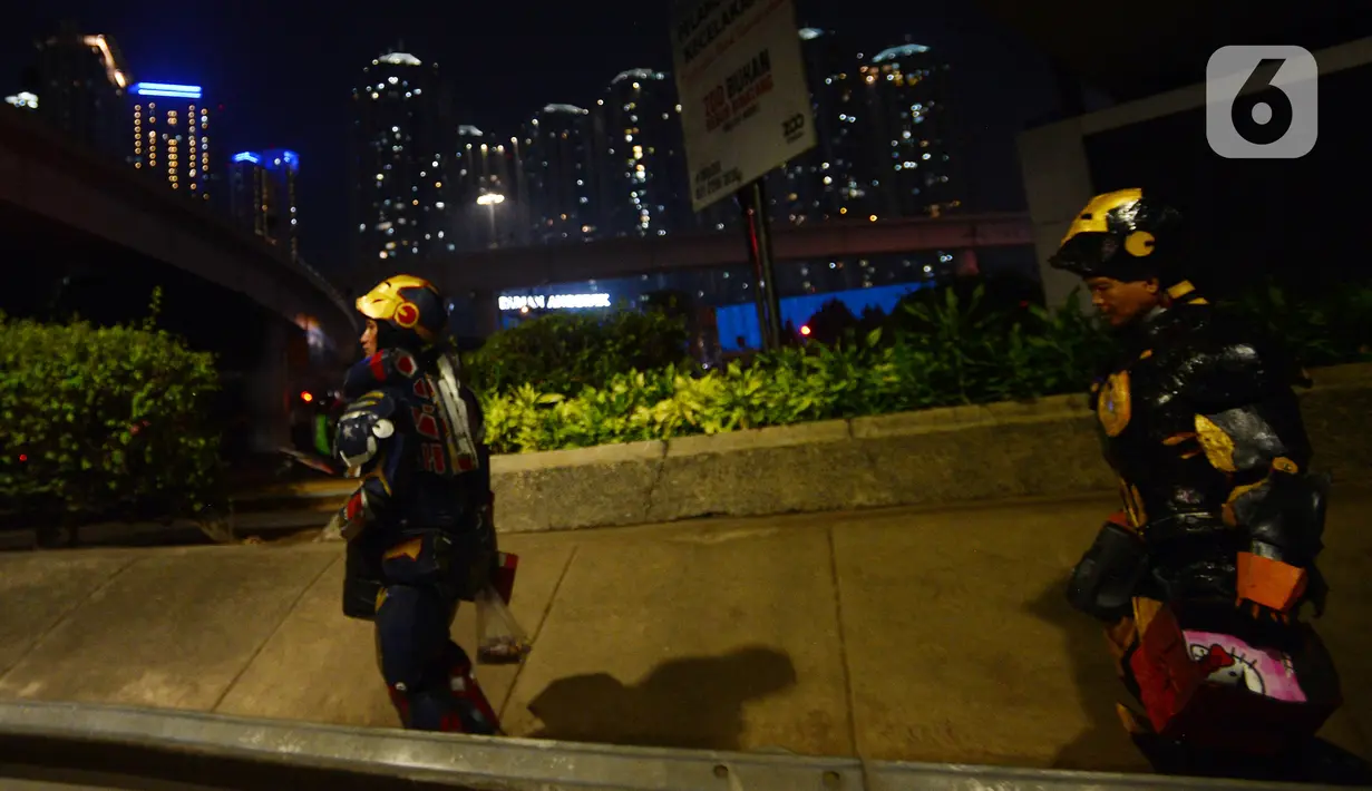 Dua robot berjalan saat menghibur pengendara di kawasan Tomang, Jakarta, Selasa (14/9/2021). Abi (20) dan Nujum (48) mengenakan kostum robot Iron Man untuk mengais rejeki dan menghibur para pengendara dari kemacetan lalu lintas yang dilakukan sejak pandemi COVID-19. (merdeka.com/Imam Buhori)