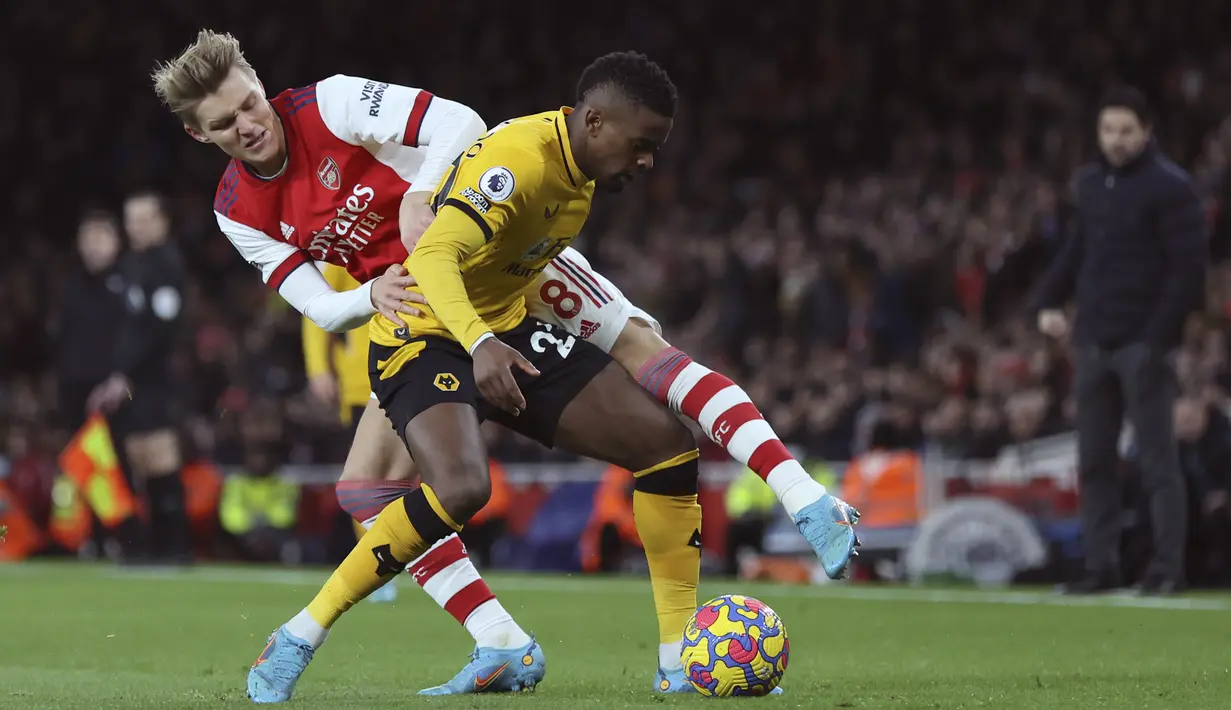 Bek Wolverhampton Wanderers Nelson Semedo berebut bola dengan gelandang Arsenal Martin Odegaard pada partai tunda pekan ke-20 Liga Inggris di Emirates Stadium, Jumat (25/2/2022) dini hari WIB. Arsenal menang dramatis 2-1 berkat dua gol di menit akhir. (AP Photo/Ian Walton)