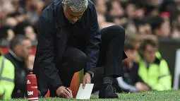 Pelatih Manchester United,  Jose Mourinho tengah mencatat hal-hal penting selama pertandingan melawan Manchester City pada laga Premier League di Old Trafford, Manchester,  (10/9/2016). (AFP/Oli Scarff)