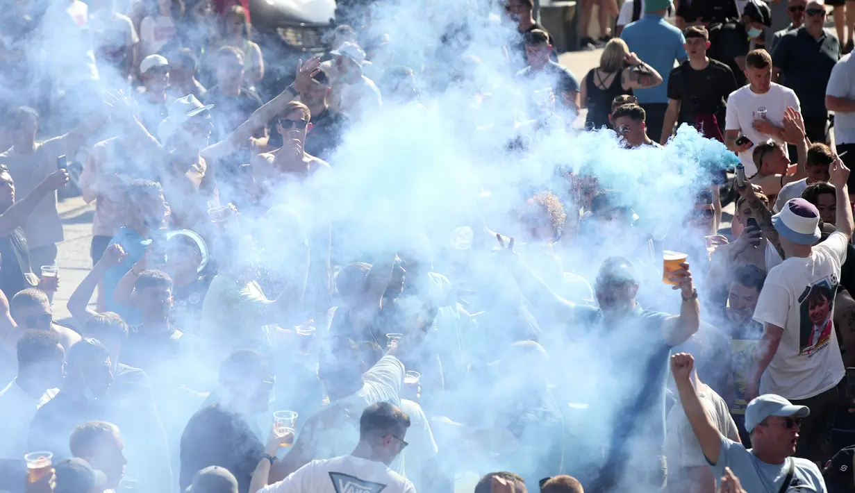 Pendukung Manchester City minum dan bernyanyi di tengah asap biru bom asap di tepi sungai Douro di Porto, Portugal (28/5/2021).  (AP Photo/Luis Vieira)