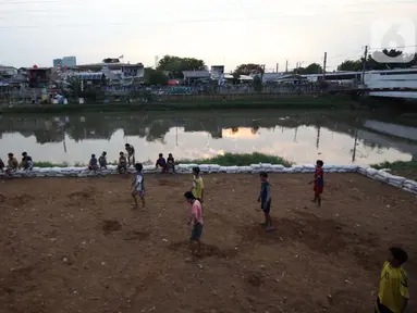 Sejumlah anak bermain sepak bola di sebuah lahan kosong di Pinggir Banjir Kanal Barat, Jakarta, Selasa (12/10/2021). Alih fungsi lahan menjadi kawasan hunian dan perkantoran mengakibatkan semakin minimnya lahan bermain bola bagi anak di Ibu kota.  (Liputan6.com/Johan Tallo)