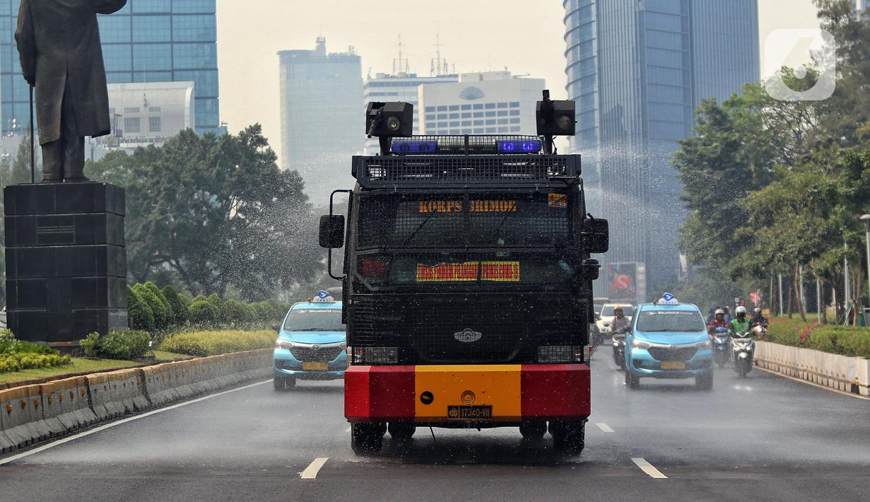 Suasana saat kendaraan water canon Brimob Polda Metro Jaya menyemprotkan air di Jalan Sudirman - Thamrin. (Liputan6.com/Angga Yuniar)