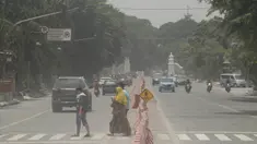 Orang-orang menyeberang jalan yang tertutup abu setelah letusan Gunung Merapi di Solo (3/3/2020). Gunung paling aktif di Indonesia tersebut meletus pada 3 Maret pukul 05.22 WIB dengan tinggi kolom 6.000 meter. (AFP Photo/Dika)