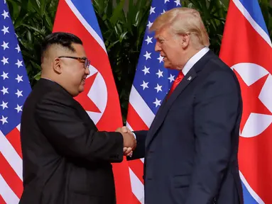 Presiden Amerika Serikat (AS) Donald Trump  berjabat tangan dengan Pemimpin Korea Utara, Kim Jong-un dalam pertemuan bersejarah di resor Capella, Pulau Sentosa, Singapura, Selasa (12/6). Trump dan Kim berjabat tangan untuk pertama kalinya. (AP/Evan Vucci)