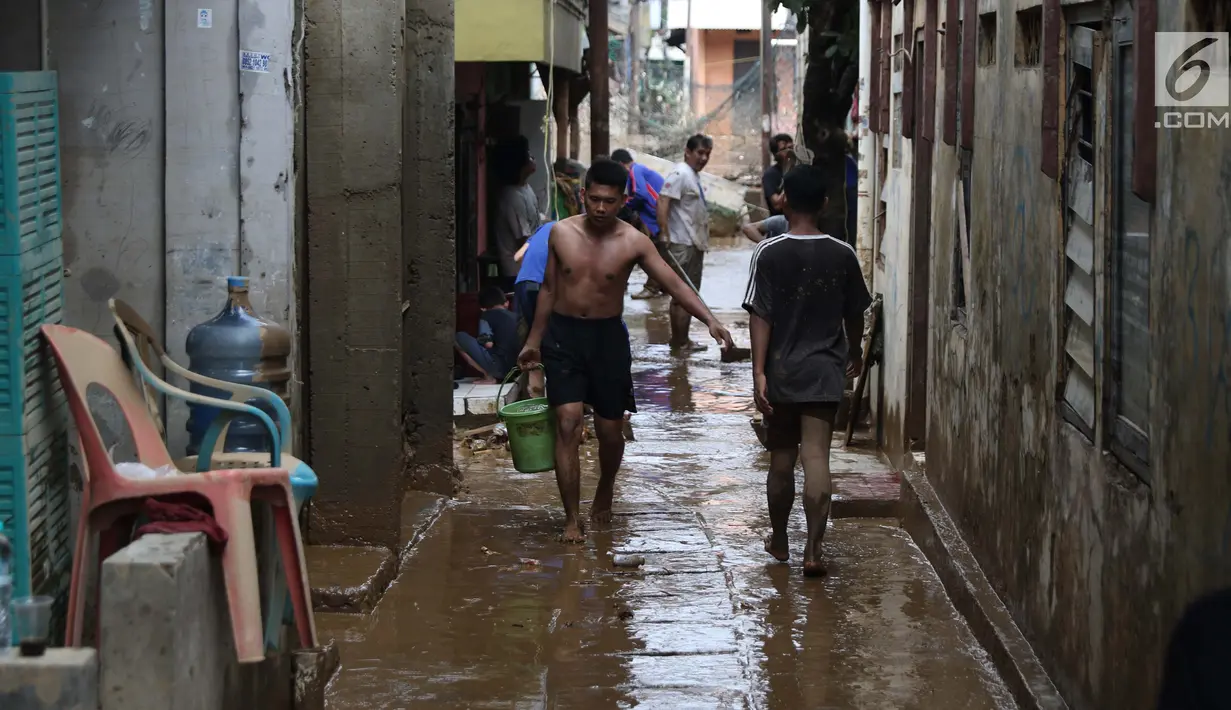 Warga membersihkan lumpur sisa banjir yang melanda kawasan Rawajati, Jakarta, Sabtu (27/4). Banjir akibat luapan air sungai Ciliwung sempat melanda kawasan ini pada Jumat (26/4). (Liputan6.com/Helmi Fithriansyah)