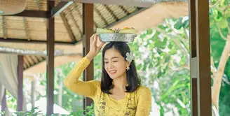 Bunga Zainal tampil cantik menawan dalam balutan kebaya Bali warna kuning dan ungu. Bunga kamboja yang diselipkan pada telinganya membuatnya terlihat lebih anggun. (Instagram/bungazainal05).