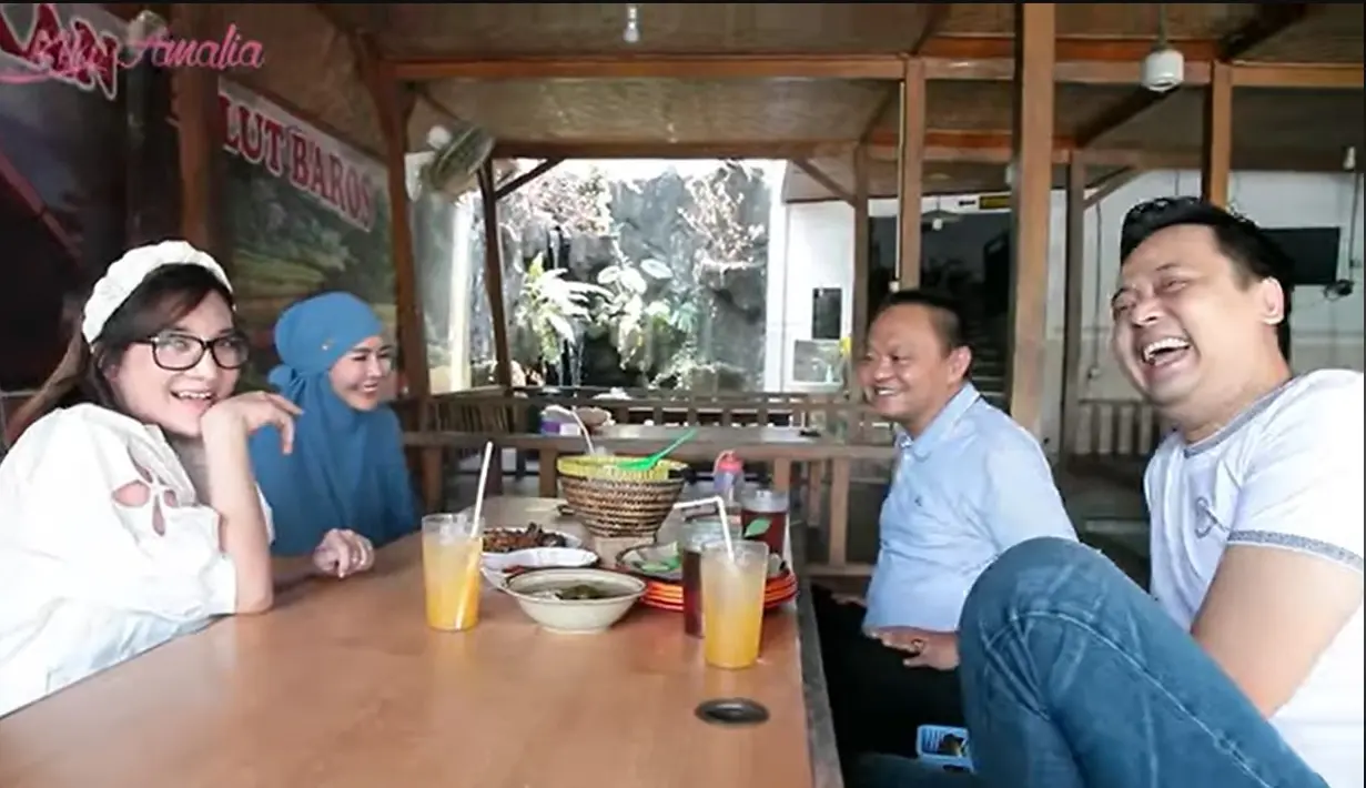Kiki dan Agung tampak kompak mengenakna putih-putih. Mereka makan di warung makan Belut Baros Hj Uum di kawasan Pandeglang, Banten. [Youtube/Kiki Amalia]