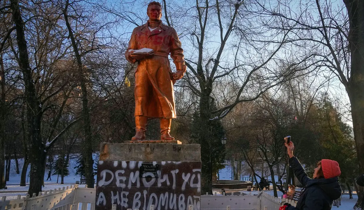 Seorang wanita mengambil foto monumen era Soviet untuk pilot Rusia Valery Chkalov sebelum pembongkaran monumen tersebut di Kyiv, Ukraina, 8 Februari 2023. Ukraina mempercepat upaya untuk menghapus sisa-sisa pengaruh Soviet dan Rusia selama berabad-abad dari ruang publik dengan merobohkan monumen dan mengganti nama ratusan jalan untuk menghormati seniman, penyair, kepala militer, dan pemimpin kemerdekaan yang tumbuh di dalam negeri. (AP Photo/Efrem Lukatsky)