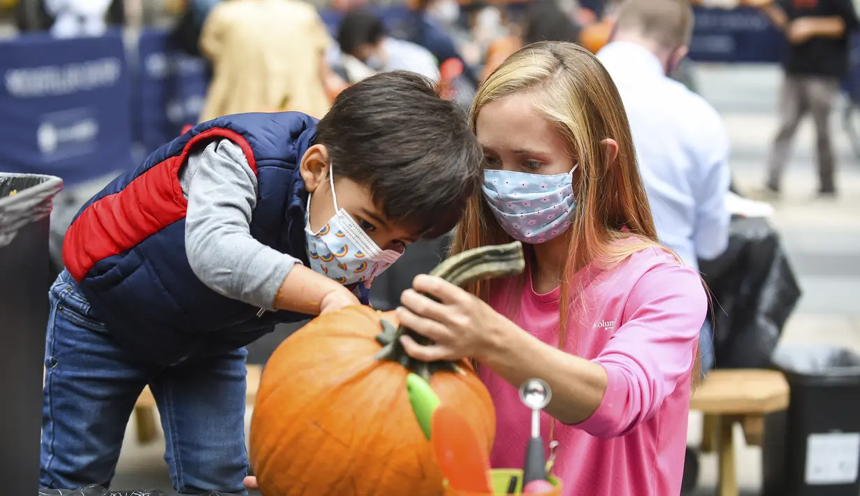 Warga New York mengukir labu dalam persiapan Halloween di Rockefeller Center (22/10/2020). Para pekerja di Rockefeller Center beristirahat sejenak untuk mempelajari cara mengukir labu dengan benar dari Maniac Pumpkin Carvers, seniman dari Brooklyn . (Diane Bondareff/AP Images for Tishman Speyer)