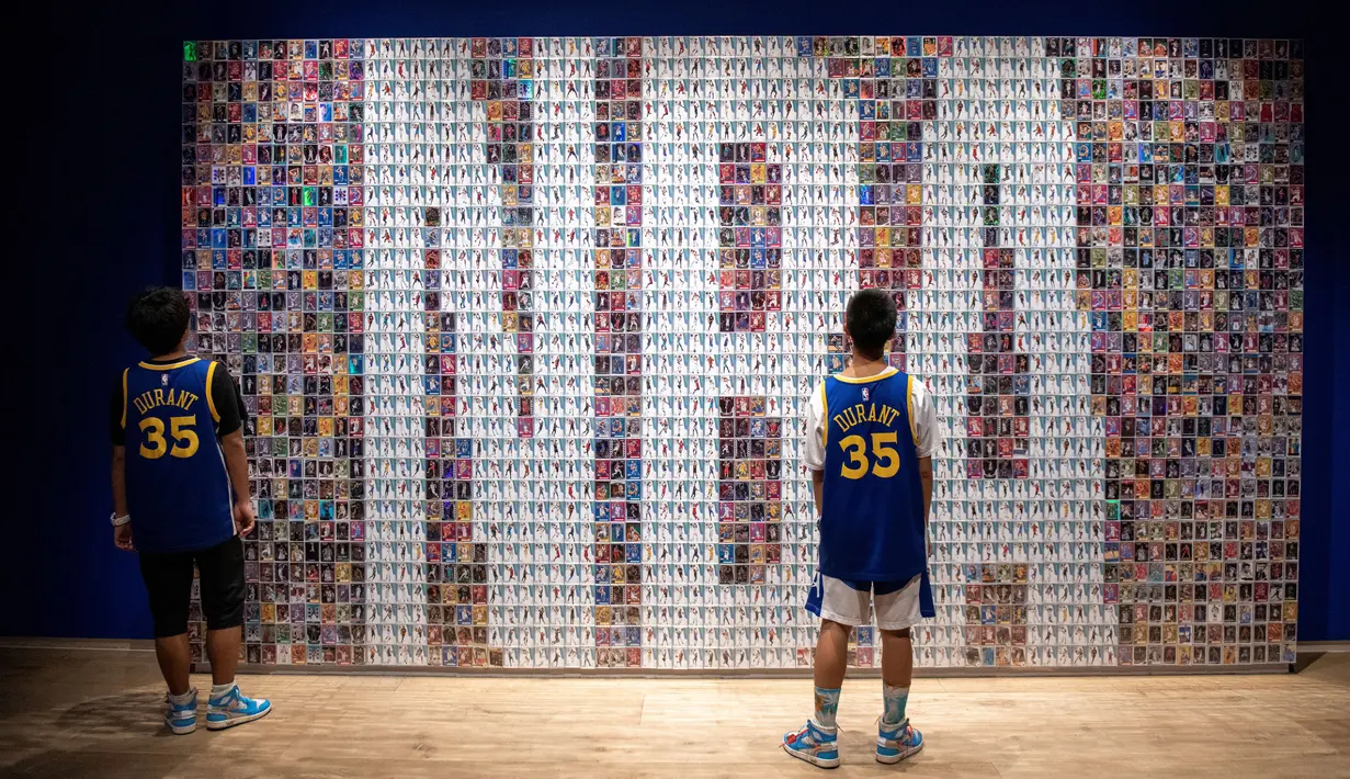 Pengunjung memandangi dinding yang memajang trading cards bola basket dalam pameran NBA (National Basketball Association) di Beijing, China, Senin (19/8/2019). (NICOLAS ASFOURI/AFP)
