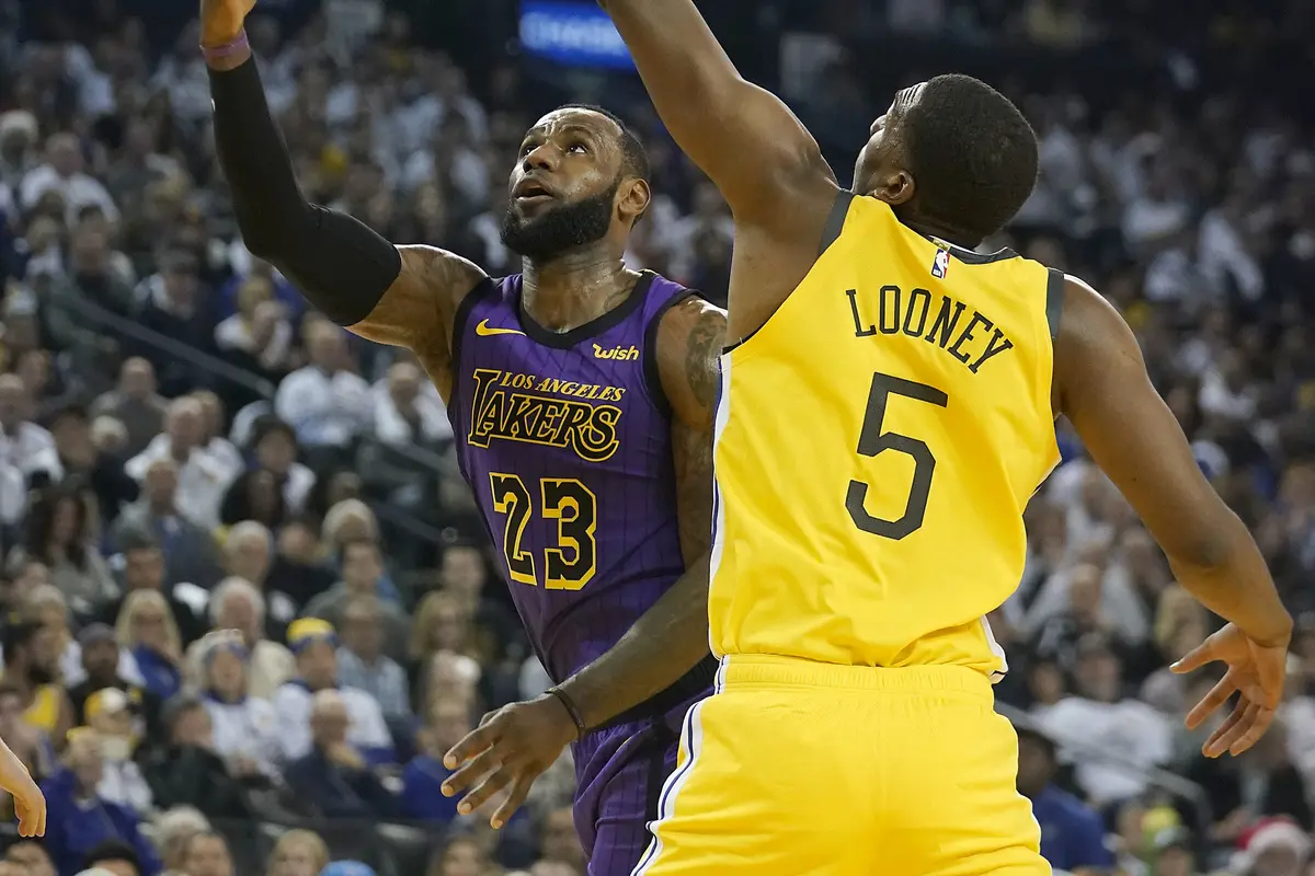 Bintang LA Lakers, LeBron James (kiri) diadang pemain Golden State Warriors, Kevon Looney