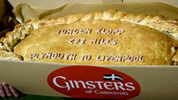 Sindiran pada Jurgen Klopp berupa kue pastel raksasa yang bertuliskan jarak tempuh Liverpool menuju Plymouth. (EPA/Gerry Penny)