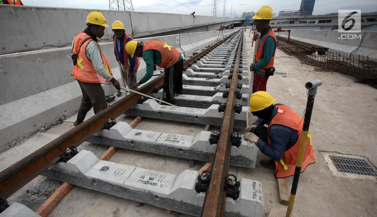 Pekerja mengerjakan pemasangan rel di Depo LRT, Kelapa Gading, Jakarta Utara, Kamis (25/1). Satu rangkaian LRT diperkirakan dapat menampung sekitar 540 penumpang. (Liputan6.com/Arya Manggala)