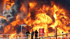 Pekerja mengamati kebakaran besar yang melanda salah satu tangki kilang minyak di Haifa, utara kota Israel, Minggu (25/12). Tidak ada korban jiwa dalam insiden yang masih belum diketahui penyebab kebakaran tersebut. (REUTERS/Baz Ratner)