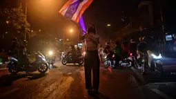 Seorang pengunjuk rasa mengibarkan bendera selama demonstrasi di Bangkok, Thailand, Minggu (6/9/2021). Aksi unjuk rasa yang menyuarakan pengunduran diri Perdana Menteri Thailand, Prayut Chan-O-Cha makin mencekam hingga malam hari. (AFP/Lillian Suwanrumpha)