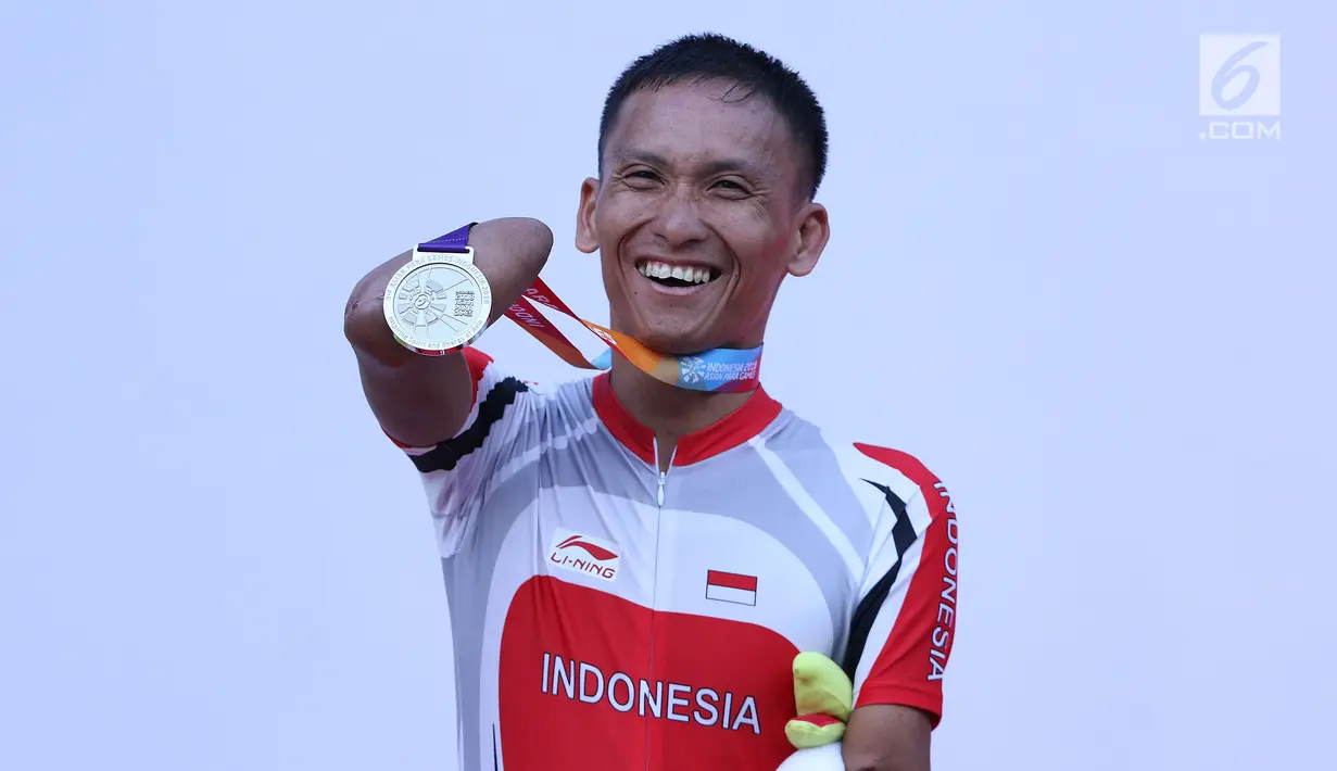 Atlet ParaCycling, Anwar Saipul memperlihatkan medali perak nomor Mens C3 Individual Time Trial Road Race Asian Para Games 2018 usai prosesi pengalungan medali di Sirkuit Sentul, Bogor, Senin (8/10). (Liputan6.com/Helmi Fithriansyah)