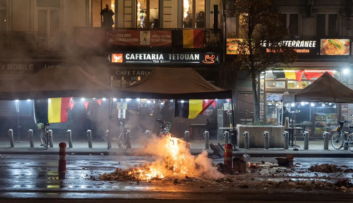 Kebakaran terlihat di depan bar selama bentrokan setelah timnas Maroko kalah dari Prancis pada laga semifinal Piala Dunia 2022, di Brussel, Belgia, Rabu (14/12/2022). Penggemar bola di Brussel terlibat bentrok seusai laga Prancis vs Maroko selesai. (Simon Wohlfahrt / AFP)
