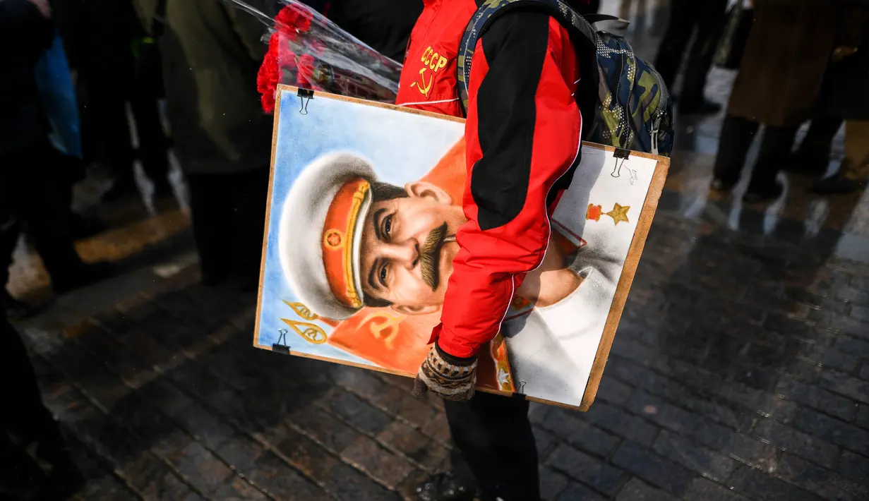Seorang wanita membawa lukisan potret Stalin saat upacara memperingati 65 tahun kematian Joseph Stalin di Lapangan Merah, Moskow (5/3). Joseph Stalin adalah pemimpin kedua Uni Soviet yang menggantikan Vladimir Lenin. (AFP/Kirill Kudryavtsev)