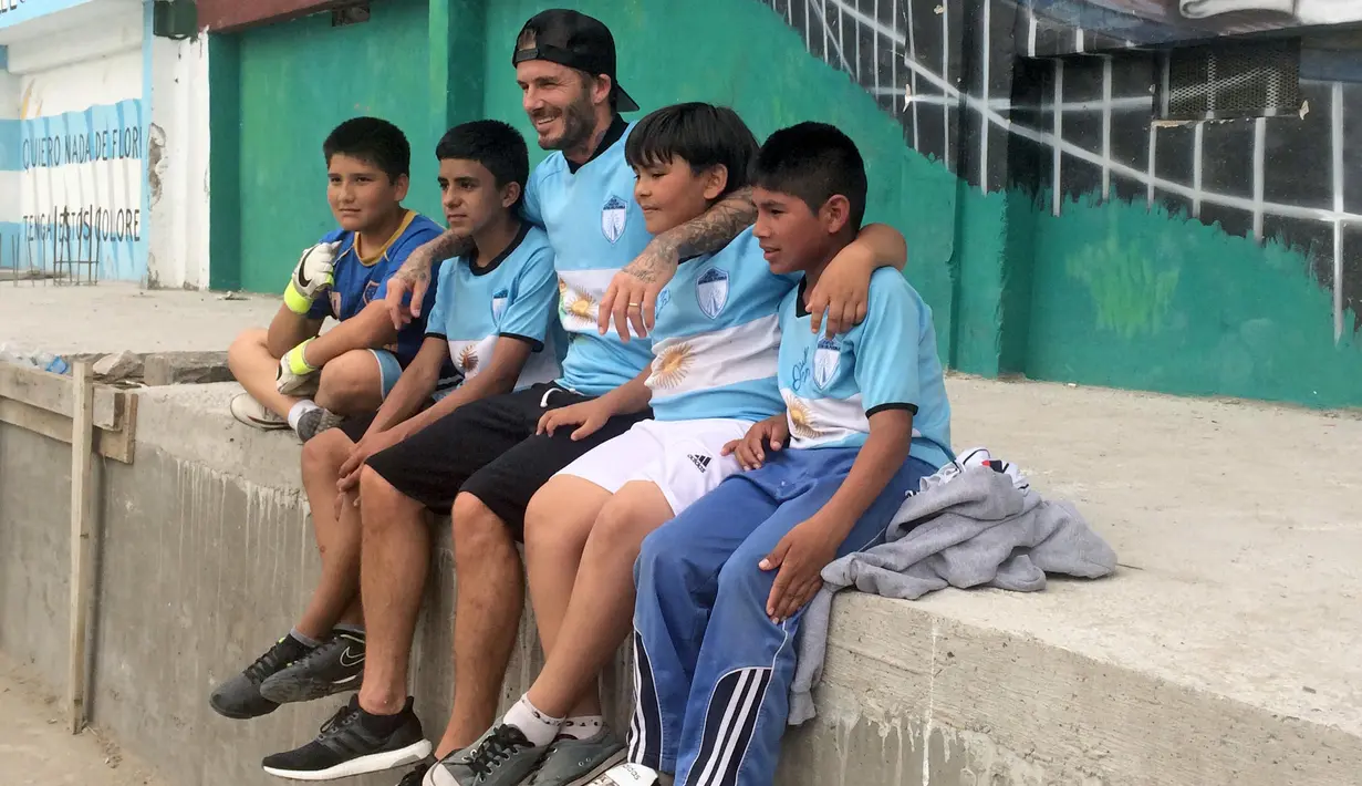 Bintang Sepak Bola David Beckham berfoto bersama anak-anak usai bermain bola untuk pembuatan film Dokumenter di Buenos Aires, Senin (9/11/2015).  (AFP Photo/FIXER-ARGENTINA/Macarena Galiardi)