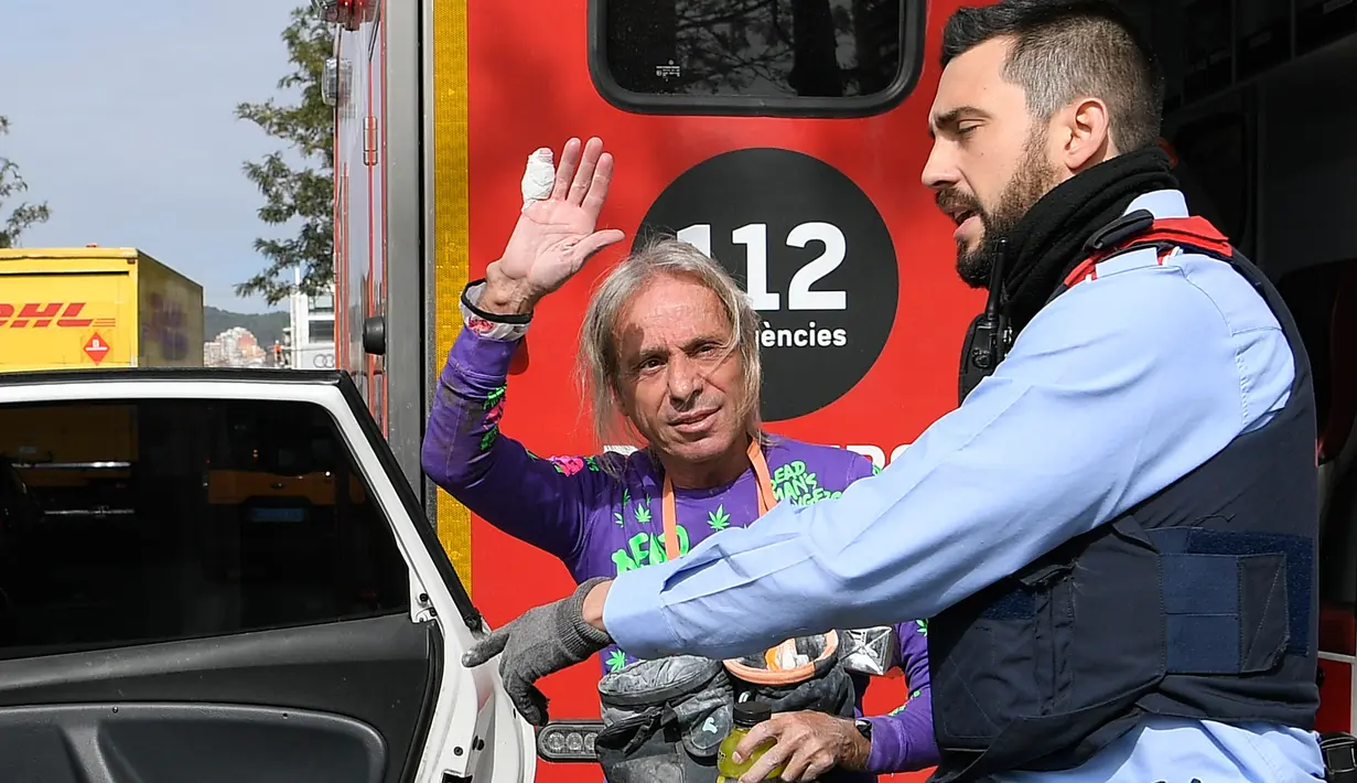 Pendaki pencakar langit, Alain Robert, yang juga dikenal sebagai 'Spiderman Prancis' melambaikan tangan saat ditahan kepolisian usai memanjat Menara Agbar setinggi 144 meter di Barcelona, Rabu (4/3/2020). Alain Robert telah menaklukkan lebih dari 100 bangunan di seluruh dunia. (LLUIS GENE/AFP)