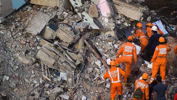 Petugas penyelamat mencari orang-orang di reruntuhan gedung apartemen berlantai lima yang runtuh di Mahad, India (25/8/2020). Polisi menyebut bangunan ini terdiri dari 47 flat. Sekitar 120 kilometer sebelah selatan Mumbai. (AFP Photo/Punit Paranjpe)