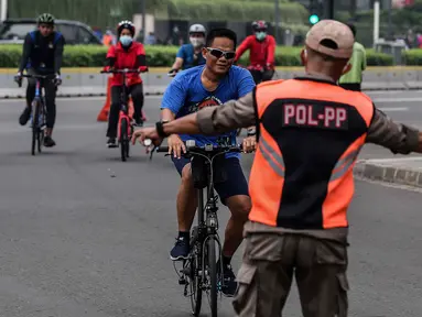 Satpol PP menghentikan pesepeda yang tidak mengenakan masker saat melintas di kawasan Bundaran HI, Jakarta, Minggu (17/1/2021). Pemerintah terus melakukan berbagai upaya guna mencegah penyebaran COVID-19 dan menurunkan angka masyarakat yang terpapar virus corona. (Liputan6.com/Johan Tallo)