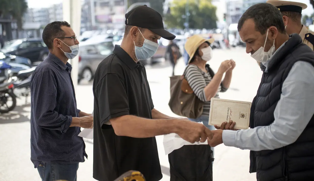 Orang-orang menunjukkan paspor vaksin sebelum diizinkan masuk memasuki kantor pemerintah, di Rabat, Maroko, Kamis (21/10/2021). Maroko mewajibkan paspor vaksin untuk mengakses kantor pemerintah, mal, pusat kebugaran, dan area publik lain untuk mendorong kampany vaksinasi. (AP Photo/Mosa'ab Elshamy)