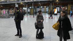 Pelancong ada di balik pita polisi di stasiun kereta Gare du Nord, Paris, Rabu (11/1/2023). Motif penyerangan yang dilakukan tersangka belum diketahui. Insiden di stasiun Gare du Nord itu telah menyebabkan kekacauan jadwal keberangkatan dan ketibaan kereta. (AP Photo/Michel Euler)