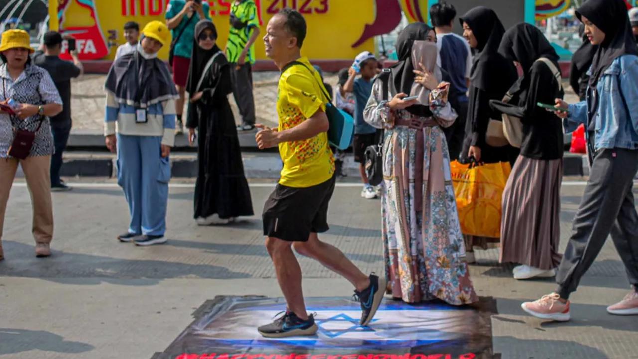 Seorang warga yang  sedang berolahraga selama CFD terlihat menginjak bendera Israel yang dibentangkan pada spanduk di jalan raya sekitar Bundaran HI.