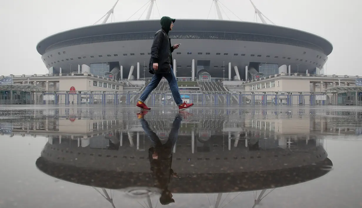 Seorang pria melintas di depan stadion sepak bola yang baru dibangun di Saint Petersburg di Rusia, Selasa (17/4). (AP Photo/Dmitri Lovetsky)