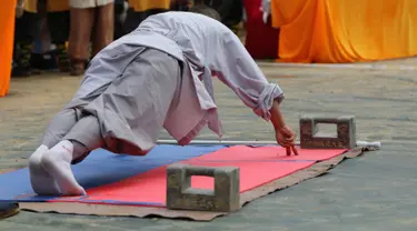 Seorang biksu menunjukkan kemampuann push up dengan dua jari selama kompetisi seni bela diri '72 Arts of Shaolin' di kuil Shaolin di Provinsi Henan, China, 30 Juli 2017. Kompetisi ini menampilkan para jago kungfu yang memamerkan kekuatan fisik. (STR AFP)