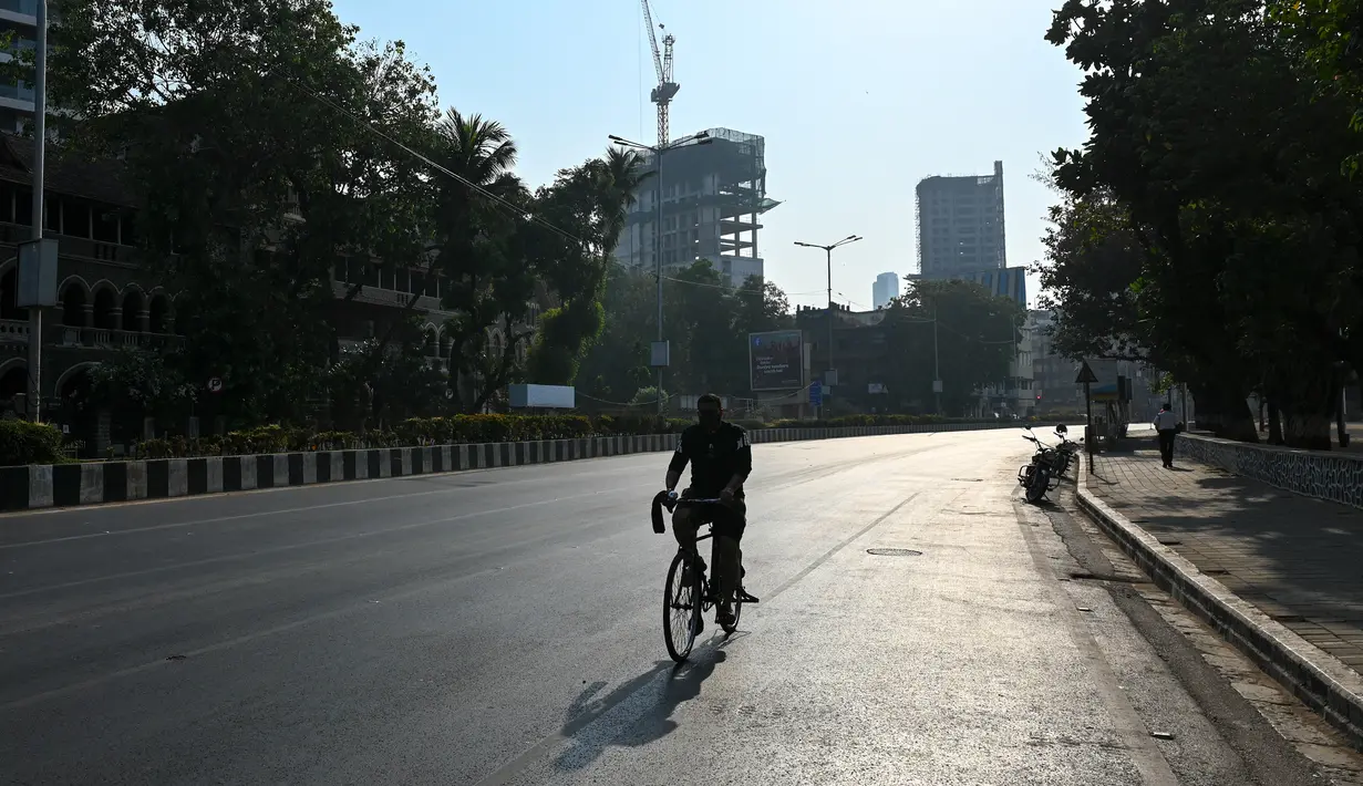 Seorang pengendara sepeda melintas di jalan sepi selama pembatasan yang diberlakukan oleh pemerintah negara bagian di tengah meningkatnya kasus corona Covid-19, di Mumbai, Kamis (15/4/2021). Kasus virus corona baru di India mencapai rekor tertinggi pada Rabu, 14 April. (Punit PARANJPE / AFP)